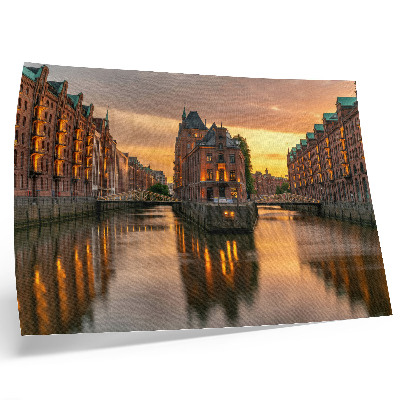 Plakat na platnu Mirna voda, zgrade od opeke, toplo svjetlo